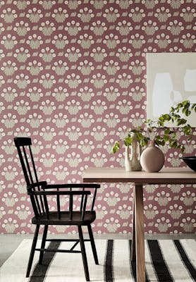 Dining room with pink printed snail wallpaper (Burges Snail - Rosie) behind a wooden dining room table and chair.