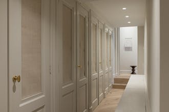 Hallway lined with neutral off-white (Portland Stone - Pale) cupboards and walls and light wooden flooring.