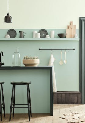 Kitchen space in varying shades of Aquamarine with a breakfast bar and stools on a wooden floor.