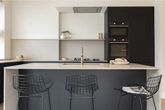 Dark kitchen cabinets and island paired with neutral Portland Stone and Portland Stone - Pale paints on the wall.