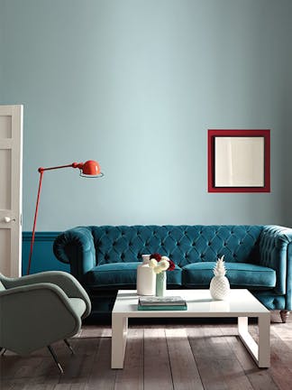 Living space with the wall painted in muted blue shade 'Celestial Blue' with a teal sofa and white coffee table.