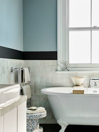 Bathroom with pale blue (Bone China Blue) upper walls and white tiles underneath, next to bathtub, window and sink.