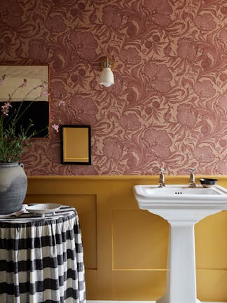 Bathroom with two-tone wall decor, featuring Poppy Trail pink floral wallpaper above and a mustard colour paint below.