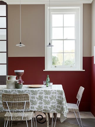 Dining room with upper wall in warm neutral 'Rolling Fog - Dark' and lower wall in deep red 'Arras', with a table and chairs.