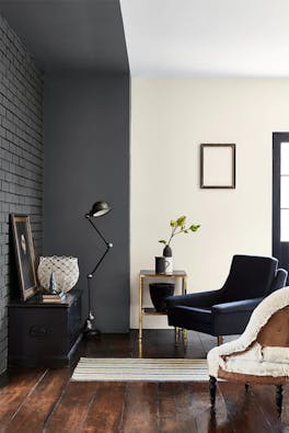 Living room with dark grey painted brickwork (Scree) with an off white wall and two armchairs facing a sidetable.