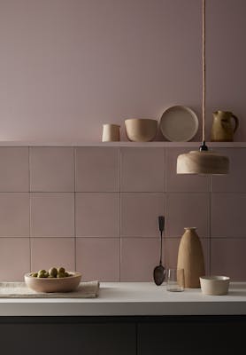 Kitchen painted in pale pink 'Chemise' with matching square tiles underneath and various kitchen utensiles on display.