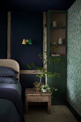 Bedroom with a dark blue back wall (Dock Blue) and the right wall in a pale green leafy wallpaper (Beech Nut - Rubine).