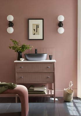 Bathroom sink area painted in blush pink shade 'Hellebore'  with darker pink 'Blush' on the vanity unit and a black sink.