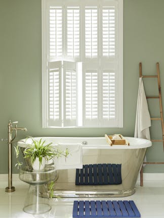 Bathroom painted in grey/ green 'Boringdon Green' with a silver bathtub under a large window.