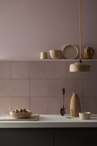 Kitchen painted in pale pink 'Chemise' with matching square tiles underneath and various kitchen utensiles on display.