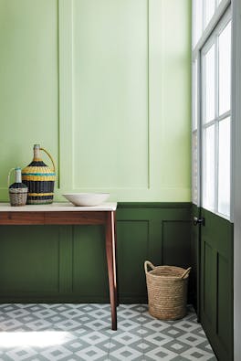 Paneled hallway with pale green (Acorn) upper wall and bold green (Hopper) lower wall with wooden sidetable and tiled floor.