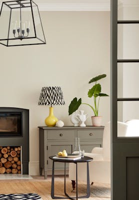 Neutral living space painted in 'Portland Stone' with grey drawers, fireplace and an armchair. 