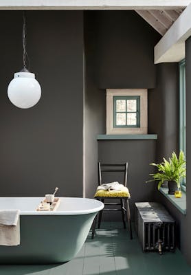 Bathroom painted in dark grey 'Vulcan' with constrasting grey, green (Livid) details with a bathtub, chair and window.