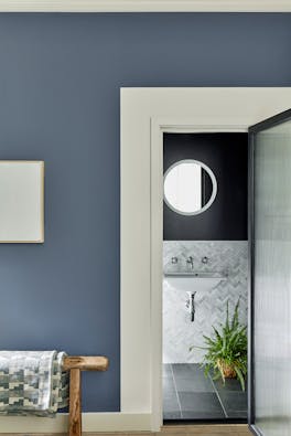 Deep blue wall (Juniper Ash) with contrasting grey woodwork looking into a tiled ensuite with a plant.