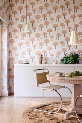 Dining room featuring pale pink tree print wallpaper (Rodney Street - Masquerade) with a white cabinet, dining room table and chairs.