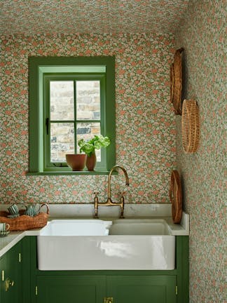 Pantry with the green and pink small print ditsy floral wallpaper 'Spring Flowers - Garden' on the walls and ceiling with dark green woodwork and a window above a sink.