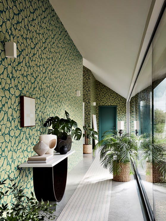 Long hallway with two tone blue and green wallpaper (Beech Nut - Florence) with a big window and plants.