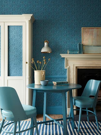 Dining space with a tonal blue wallpaper (Hoja - Air Force Blue) and white (Shirting) cupboard with blue table and chairs.