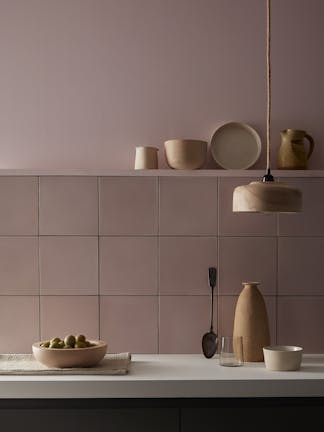 Kitchen painted in pale pink 'Chemise' with matching square tiles underneath and various kitchen utensiles on display.