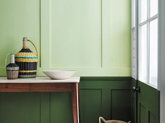 Paneled hallway with pale green (Acorn) upper wall and bold green (Hopper) lower wall with wooden sidetable and tiled floor.