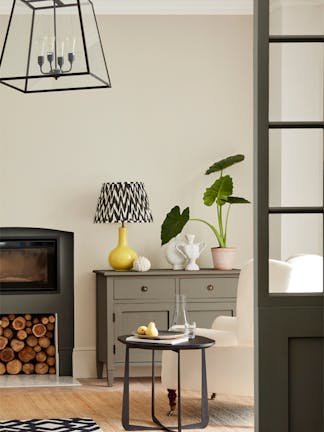 Neutral living space painted in 'Portland Stone' with grey drawers, fireplace and an armchair.