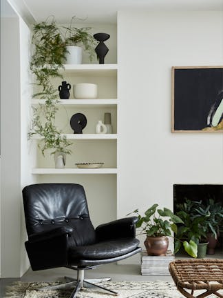 Living room with off-white (Slaked Lime - Mid) walls, a bright white (Loft White) ceiling, a leather chair and shelves.