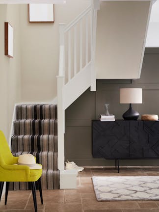 Home entryway with panelling in warm brown shade 'Attic II' and carpeted stairs with pale neutral walls and woodwork.