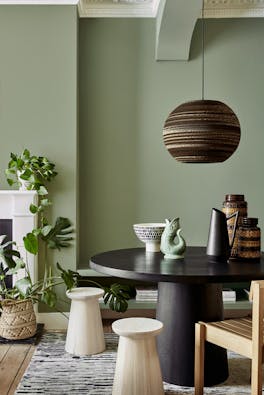 Dining area with the walls painted in calming Sage Green with a black table, stools and a chair.