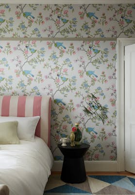 Bedroom featuring grey floral and bird wallpaper (Aderyn - French Grey) with a pink striped bed and sidetable.