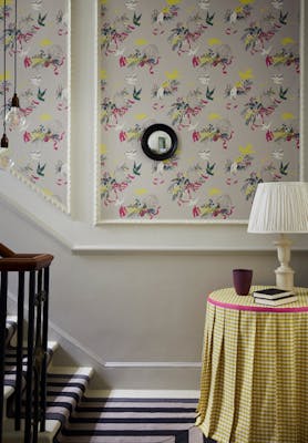 Bottom of stairs with grey bird print wallpaper (Voliéres - French Grey) and a small table with yellow gingham tablecloth.