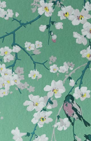 Close-up of green floral wallpaper (Massingberd Blossom - Verditer) featuring birds with white vases in the foreground.