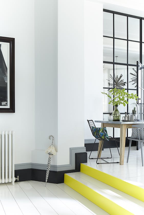 White stairs in a hallway with bright yellow (Trumpet) contrasting stair risers and a black and grey baseboard.