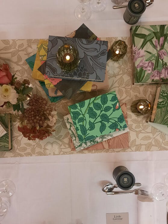 Aerial view of National Trust Papers III press event table centerpieces featuring books covered with wallpaper.