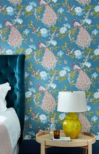 Close-up of blue wallpaper (Povona - Sylvie) featuring trees, flowers, birds, butterflies and peacocks.