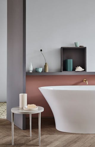 A bathtub in front of a wall with the lower half in a muted pink (Blush) and the upper wall in grey (Gauze - Dark).