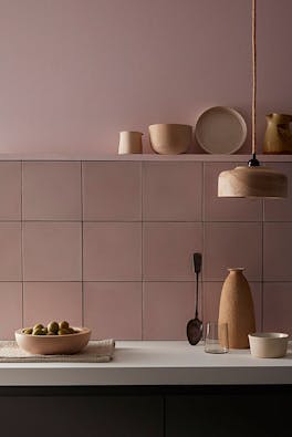 Kitchen painted in pale pink 'Chemise' with matching square tiles underneath and various kitchen utensiles on display.