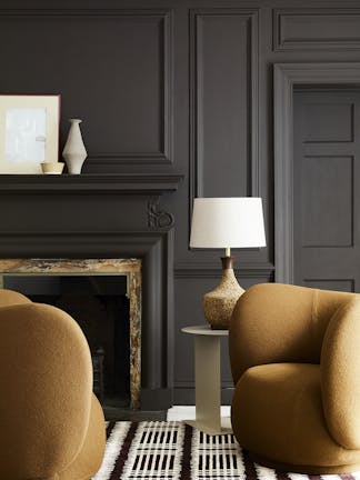 Deep brown paneled living space (Chocolate Color) with constrasting dark yellow armchairs sat next to a fireplace and lamp.