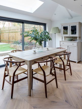 A kitchen scheme with pure white (Slaked Lime) walls, skylights, glass doors leading into the garden and wooden dining set.