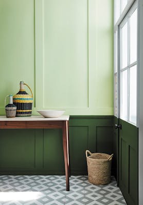 Paneled hallway with pale green (Acorn) upper wall and bold green (Hopper) lower wall with wooden sidetable and tiled floor.