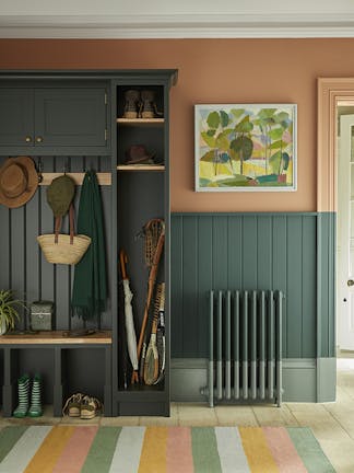 Paneled boot room with the top half painted in 'Split Pink' and the lower wall in 'Harley Green' with a cupboard to the left and a multi-colored stripy rug.