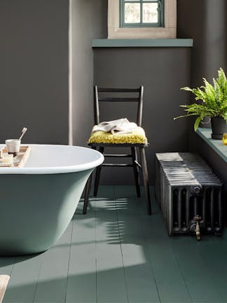 Bathroom painted in dark grey 'Vulcan' with constrasting grey, green (Livid) details with a bathtub, chair and window.