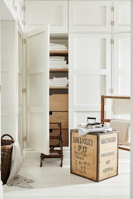 Laundry room color drenched in off white 'Linen Wash' with the closet door opened showing wooden drawers and folded laundry.