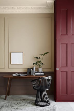 Warm neutral (Castell Pink) home study area with a red (Arras) door next to a wooden desk and chair. 