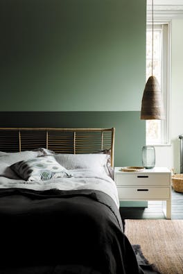 Bedroom with the upper wall painted in Aquamarine and the lower wall in Aquamarine - Pale with a double bed and side table.