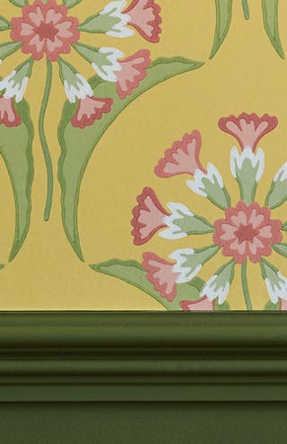 Close-up of bright yellow floral wallpaper (Hencroft - Punch) alongside dark green (Jewel Beetle) dado rail and blue jug.