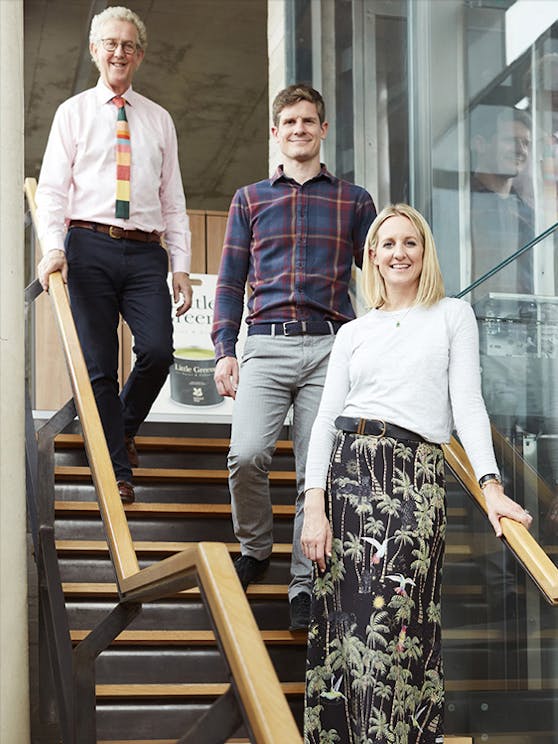 David, Ben and Ruth Mottershead stood on wooden stairs at the Little Greene office in Manchester 