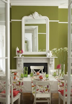 Dining room painted in vibrant green (Citrine) with contrasting off-white woodwork and a dining room table and chairs.