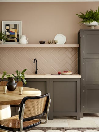 Kitchen painted in muted pink shade 'Mochi' with contrasting neutral brown 'Attic II' units with a dining room table and chair.