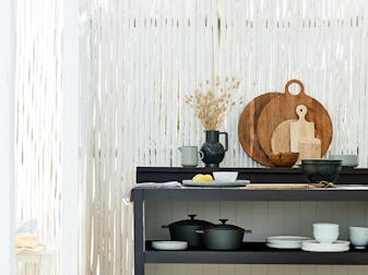 Outdoor kitchen area with bamboo fence painted in Loft White paint, with shelving displaying crockery and boards.