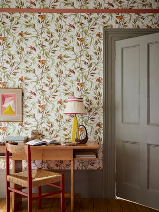 Home office space featuring bird and leaf wallpaper (Great Ormond St - Galette) with a grey door, wooden desk and chair.